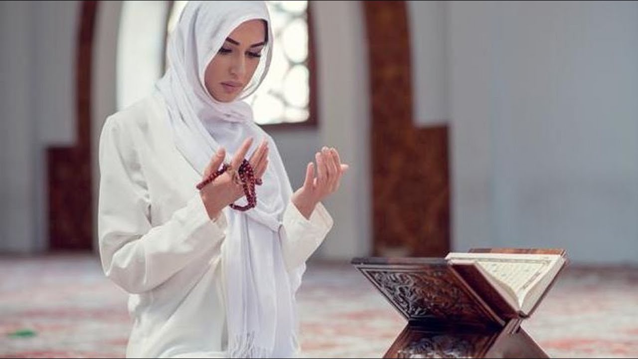 Muslim women raising hands in supplication while reading a daily dua outdoors